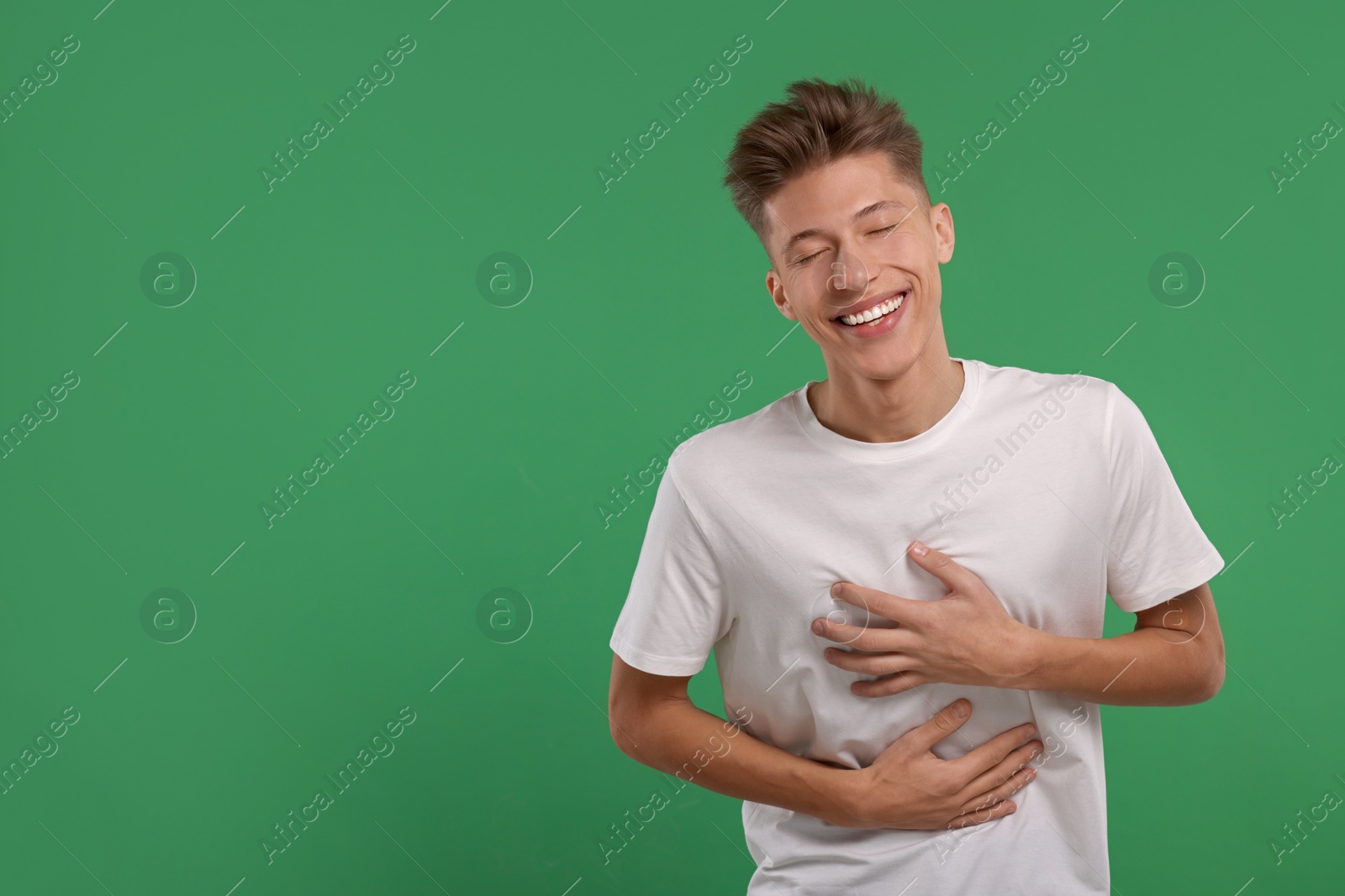 Photo of Portrait of young man laughing on green background. Space for text