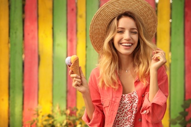 Photo of Happy young woman with delicious ice cream in waffle cone outdoors. Space for text