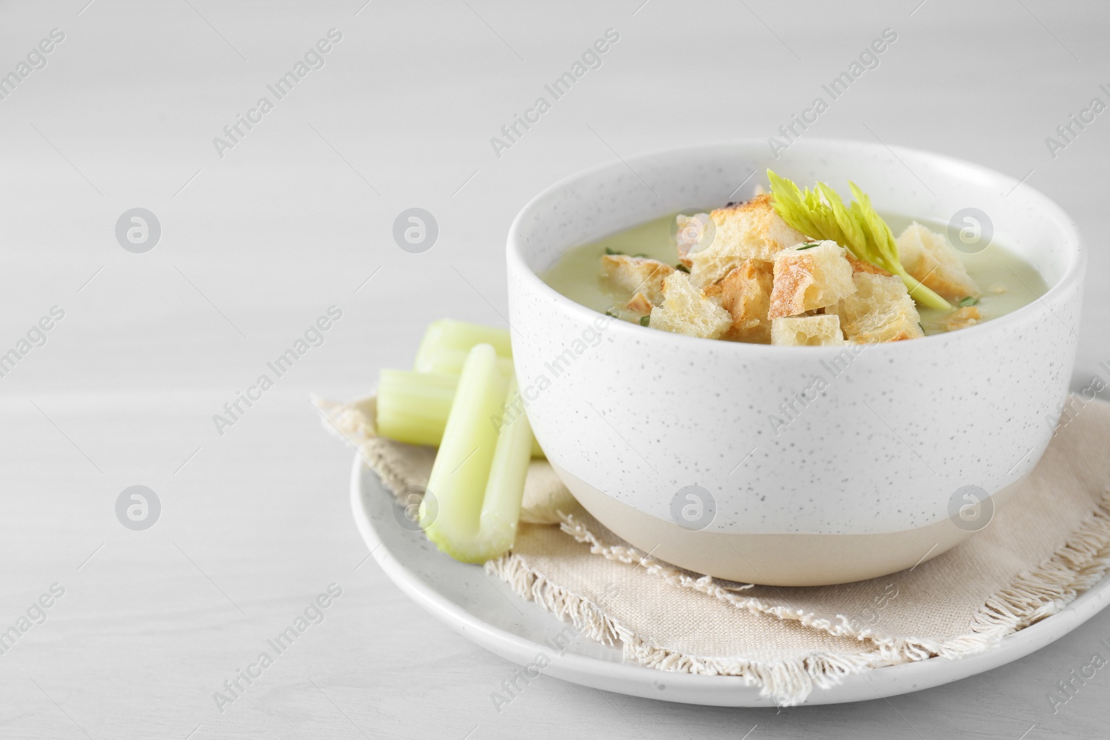 Photo of Bowl of delicious celery soup on white table, closeup. Space for text