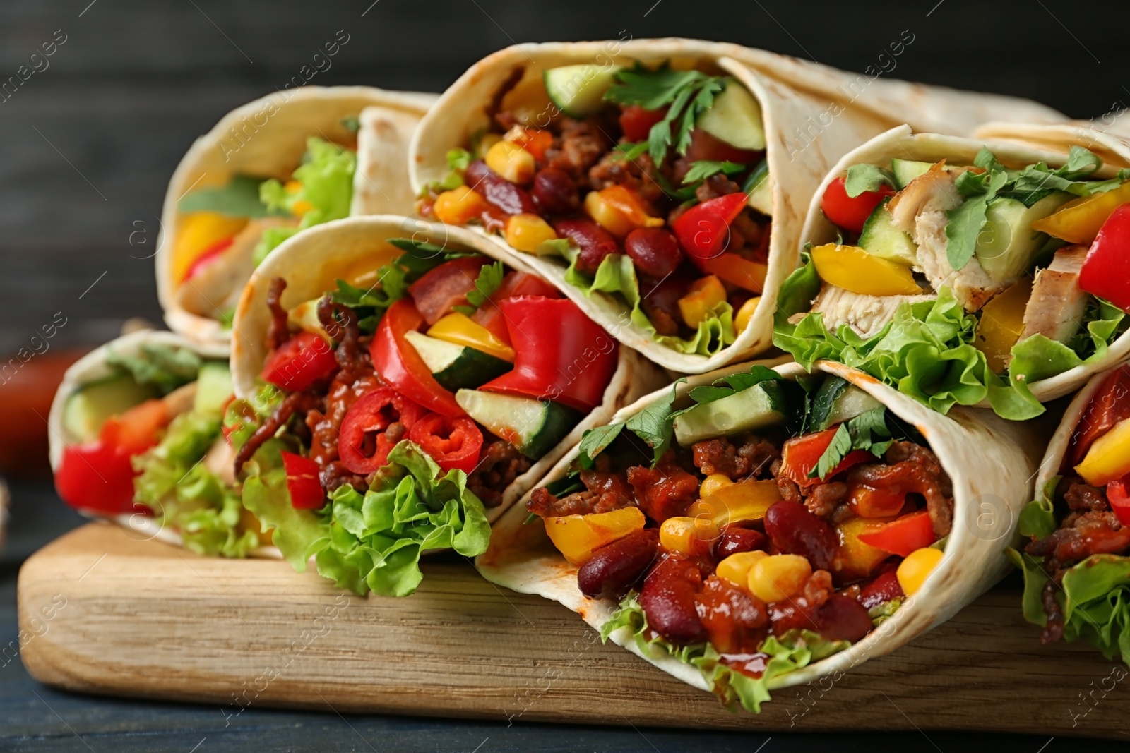 Photo of Board with delicious meat tortilla wraps on table, closeup