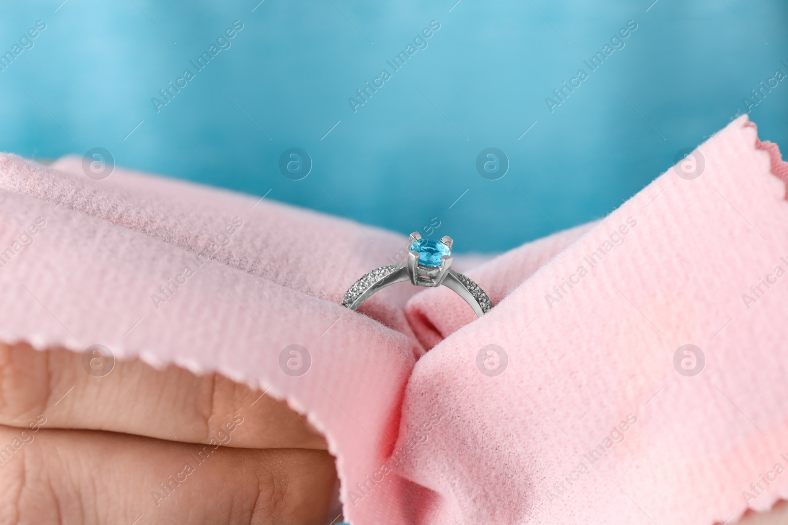 Photo of Jeweler cleaning topaz ring with microfiber cloth, closeup