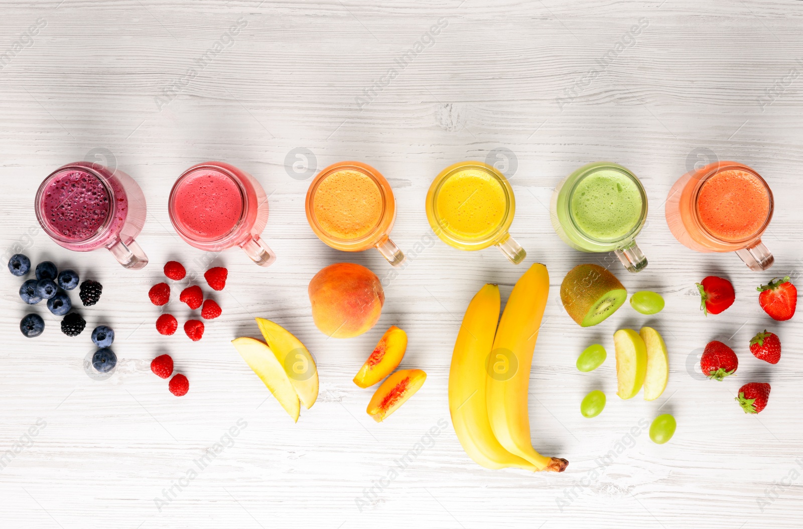 Photo of Many different tasty smoothies and ingredients on white wooden table, flat lay