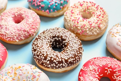 Photo of Delicious glazed doughnuts with sprinkles on color background