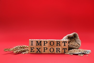 Photo of Words Import and Export made of wooden cubes, bag with wheat grains on red background