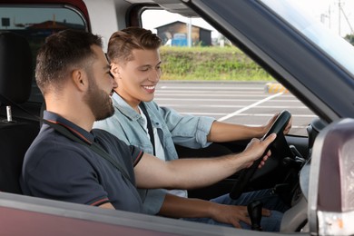 Driving school. Happy student during lesson with driving instructor in car at parking lot