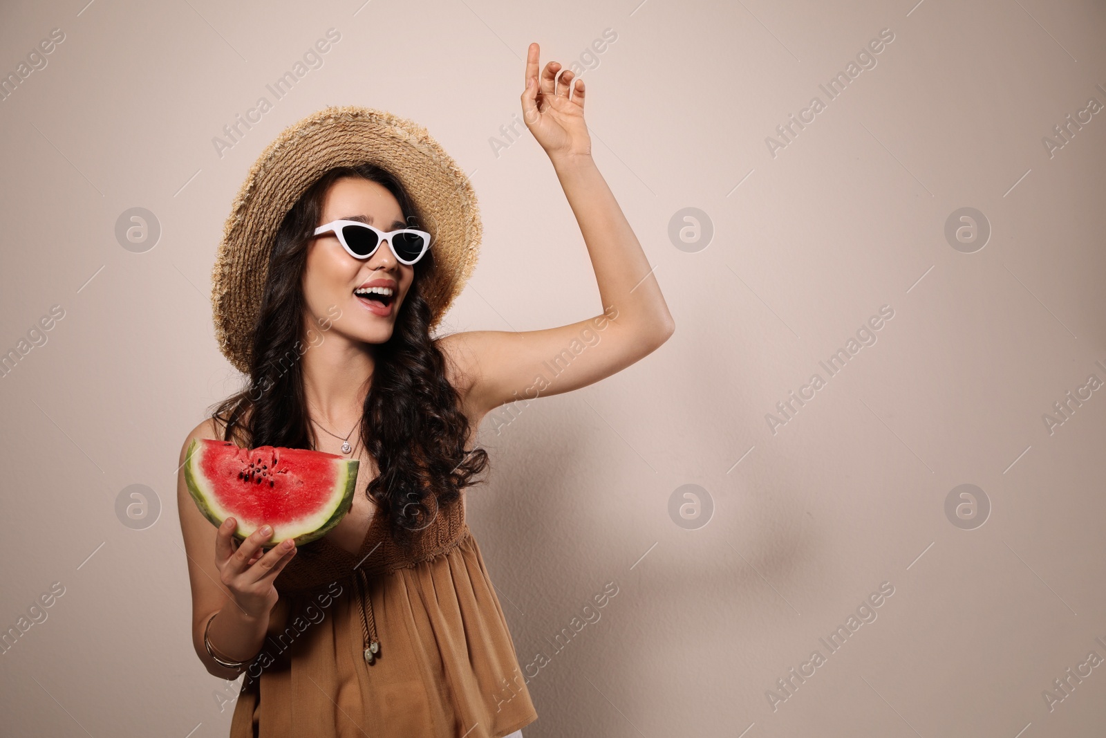 Photo of Beautiful young woman with watermelon on beige background. Space for text