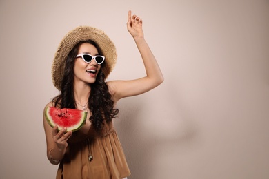 Beautiful young woman with watermelon on beige background. Space for text