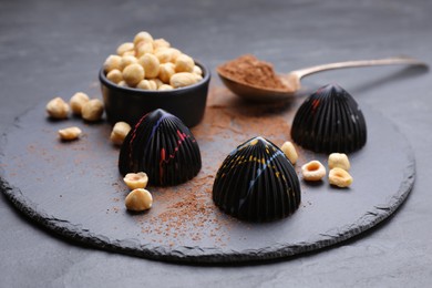 Photo of Tasty chocolate candies and nuts on grey table