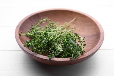 Bowl with aromatic green thyme on white wooden table, closeup. Fresh herb