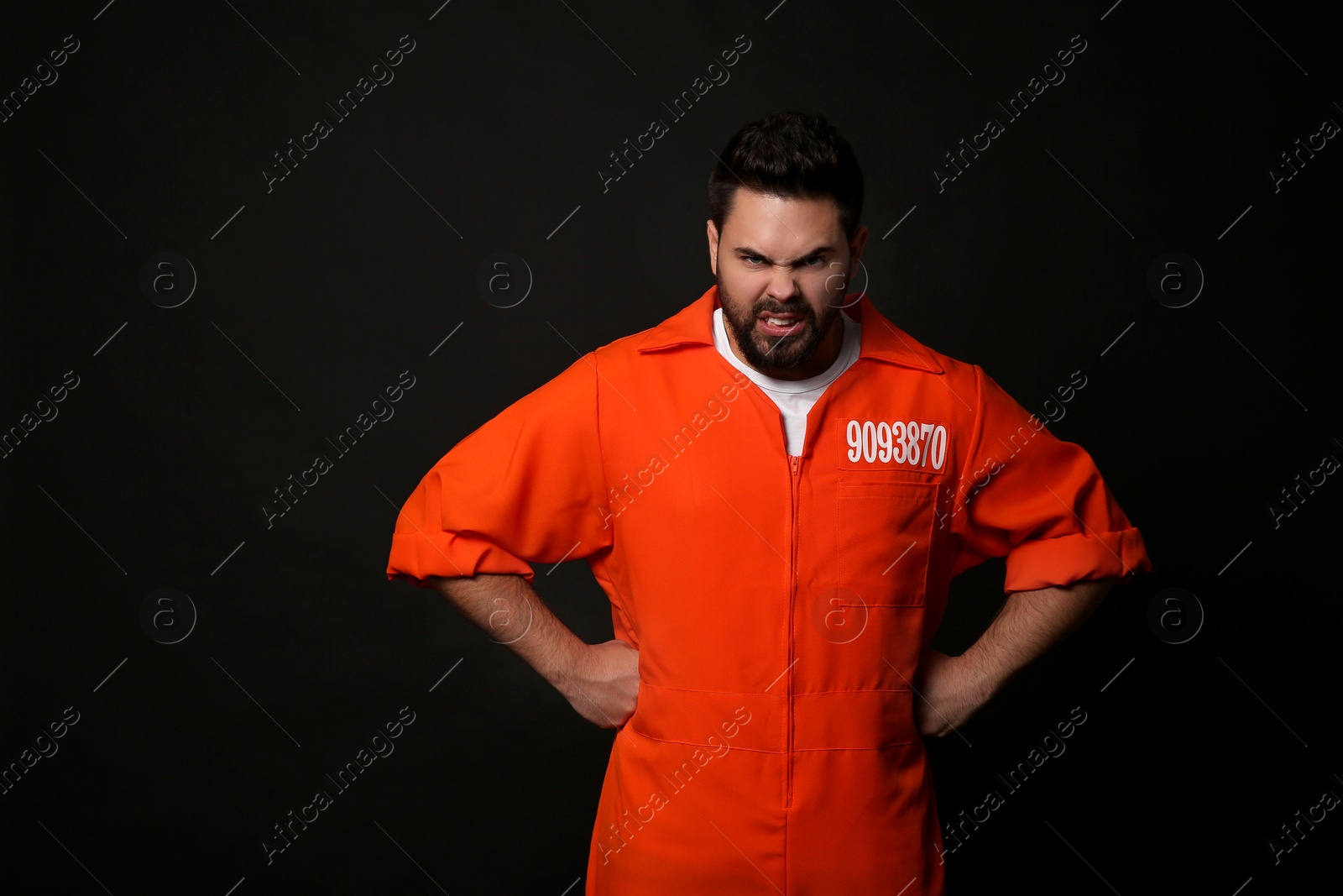 Photo of Angry prisoner in jumpsuit on black background