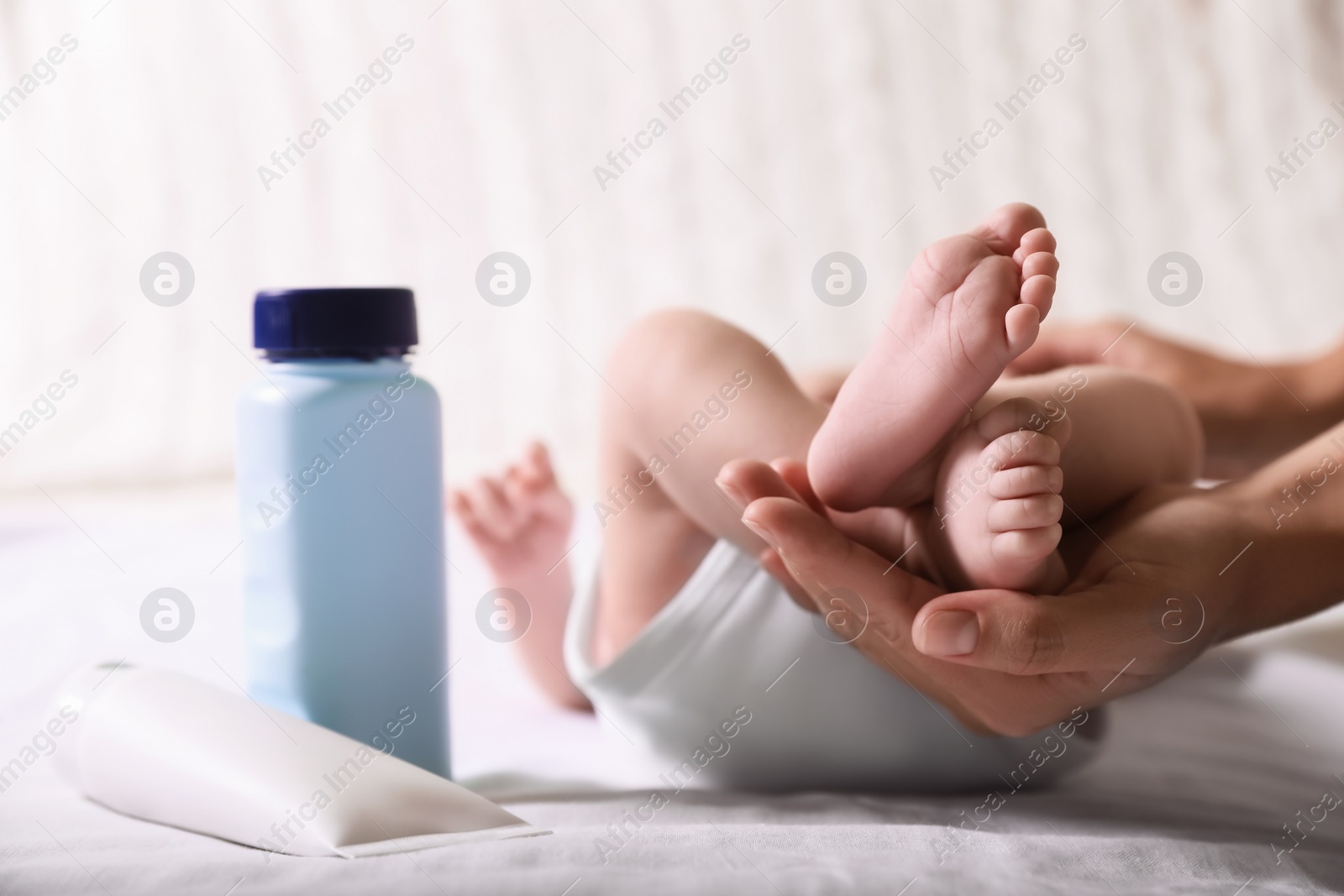 Photo of Mother holding baby`s legs on bed, closeup