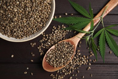 Organic hemp seeds and leaves on wooden table, flat lay