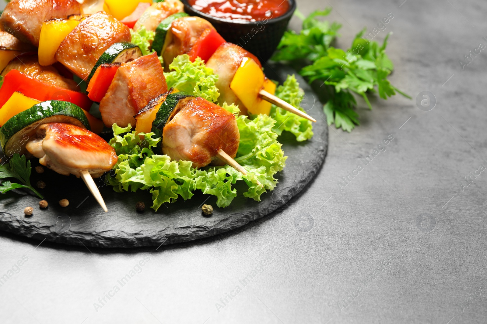 Photo of Delicious chicken shish kebabs with vegetables on grey table. Space for text