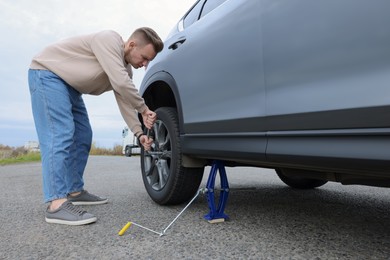 Photo of Young man changing tire of car on roadside