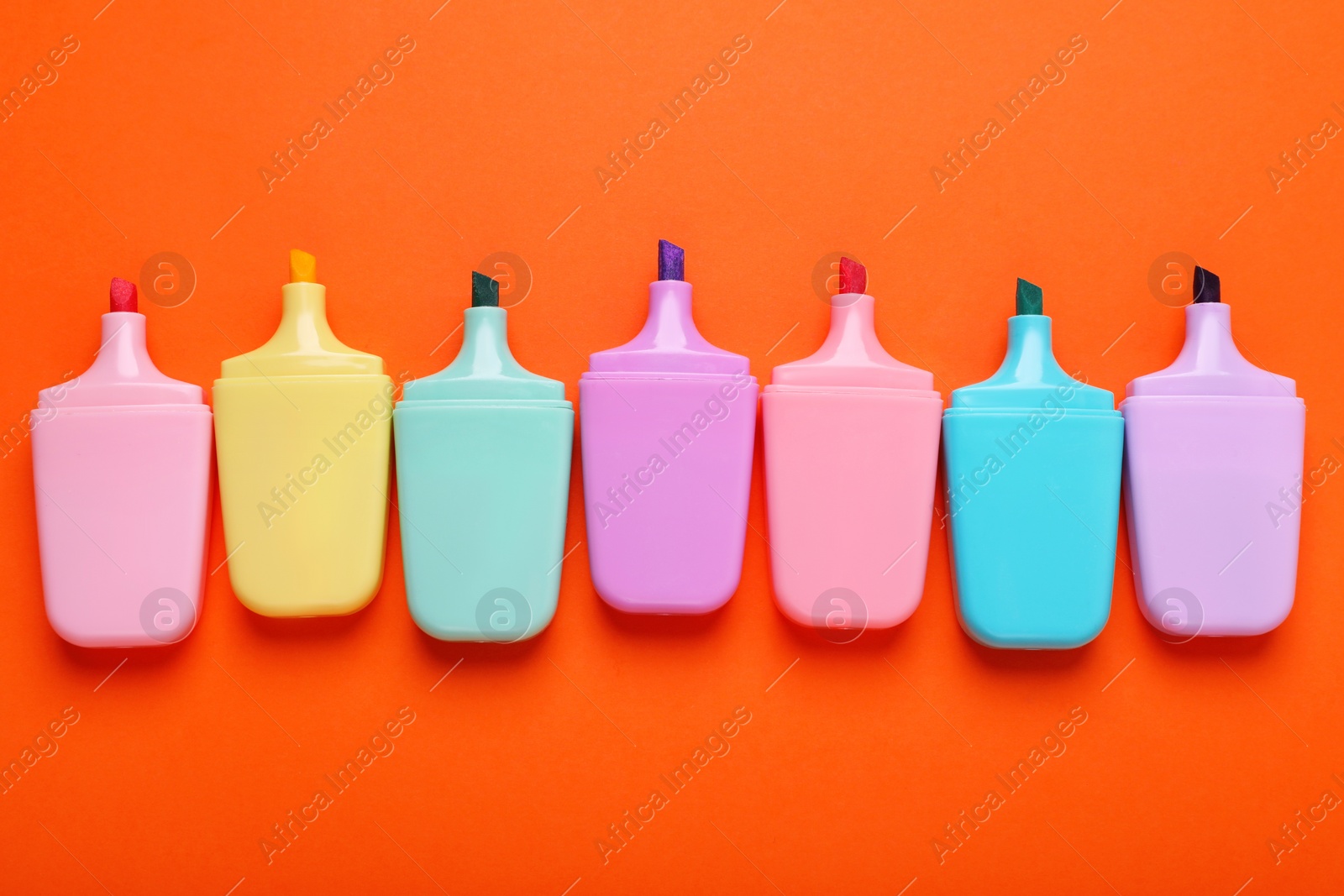 Photo of Many colorful markers on orange background, flat lay