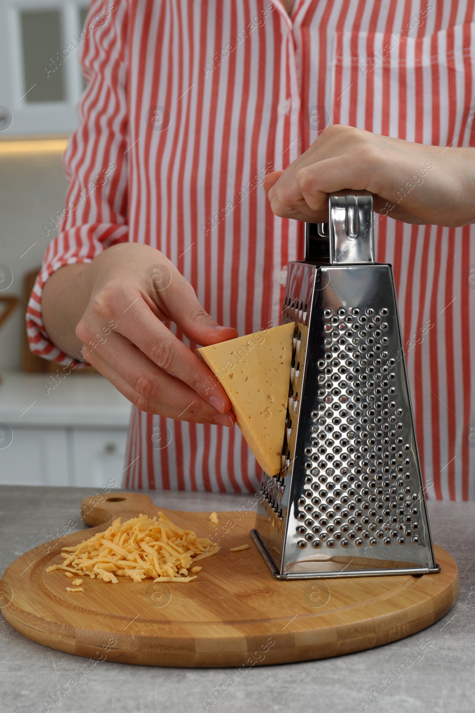 Photo of Woman grating cheese at kitchen table, closeup