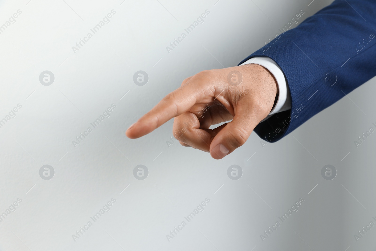 Photo of Man pointing at something on light background, closeup