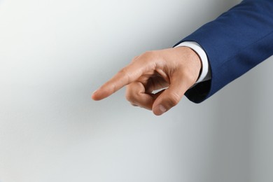 Man pointing at something on light background, closeup