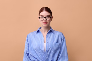 Portrait of beautiful woman in glasses on beige background