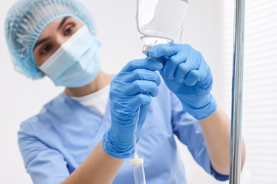 Photo of Nurse setting up IV drip in hospital, selective focus