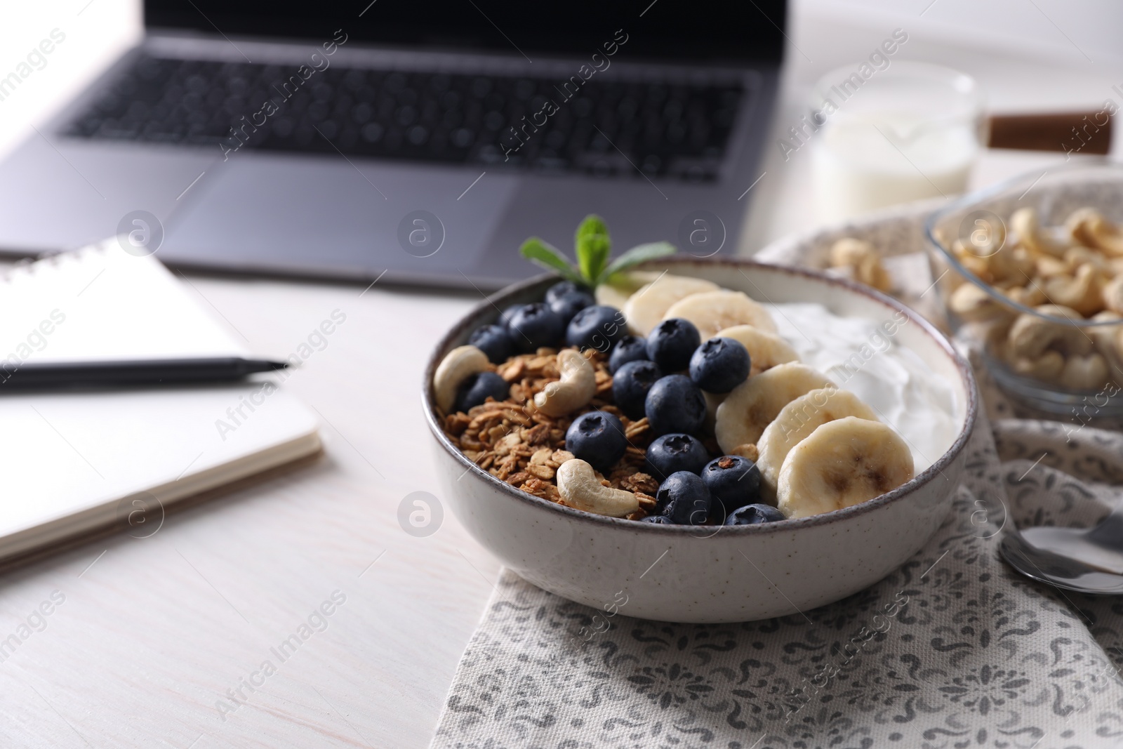 Photo of Delicious granola in bowl on white wooden table, closeup