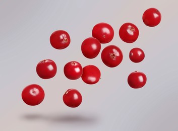 Image of Delicious ripe cranberries flying on light grey background