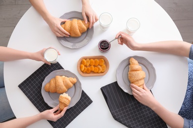 Photo of Women having tasty breakfast with fresh croissants at table, top view