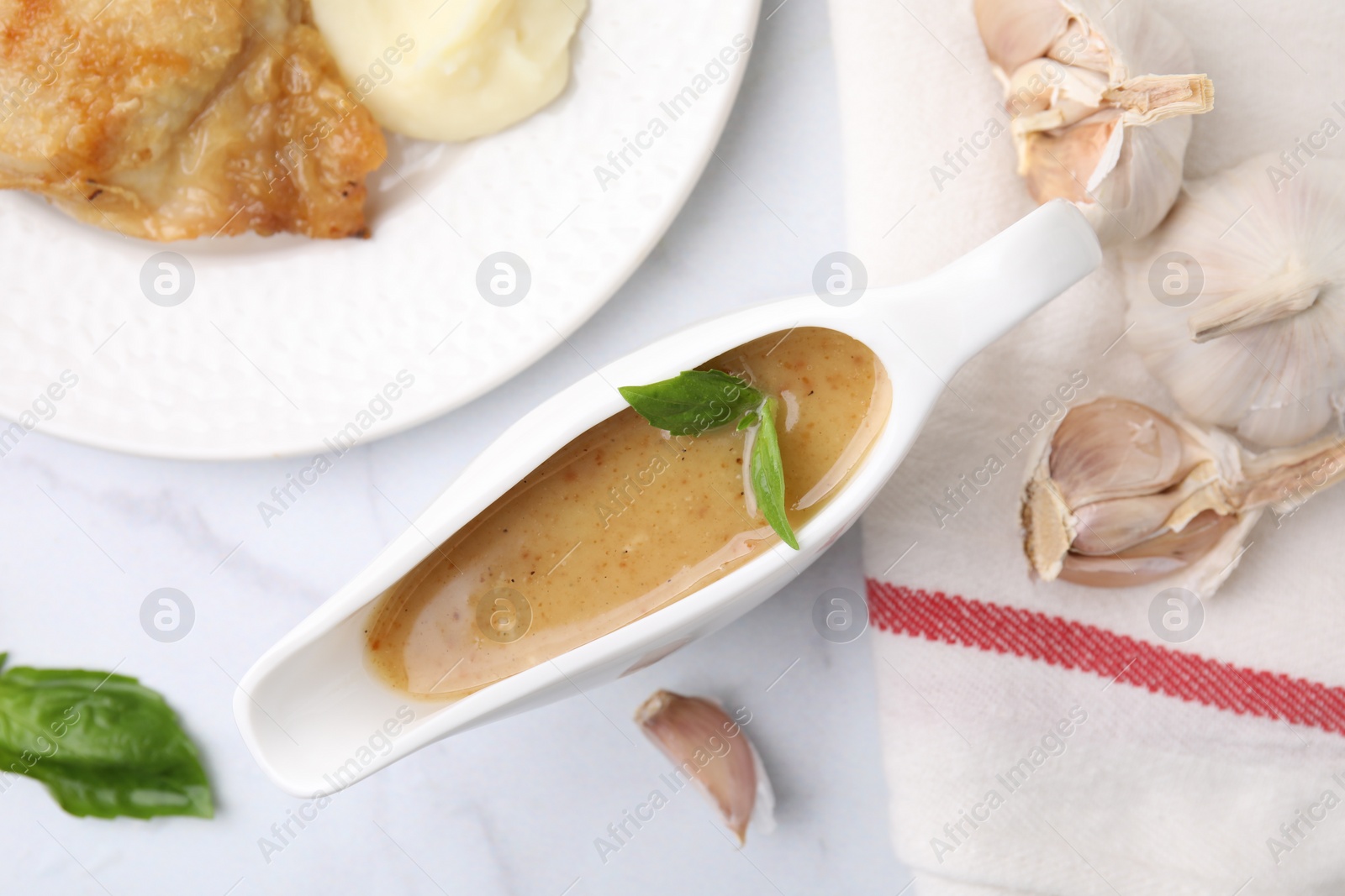 Photo of Delicious turkey gravy, basil and garlic on white marble table, flat lay