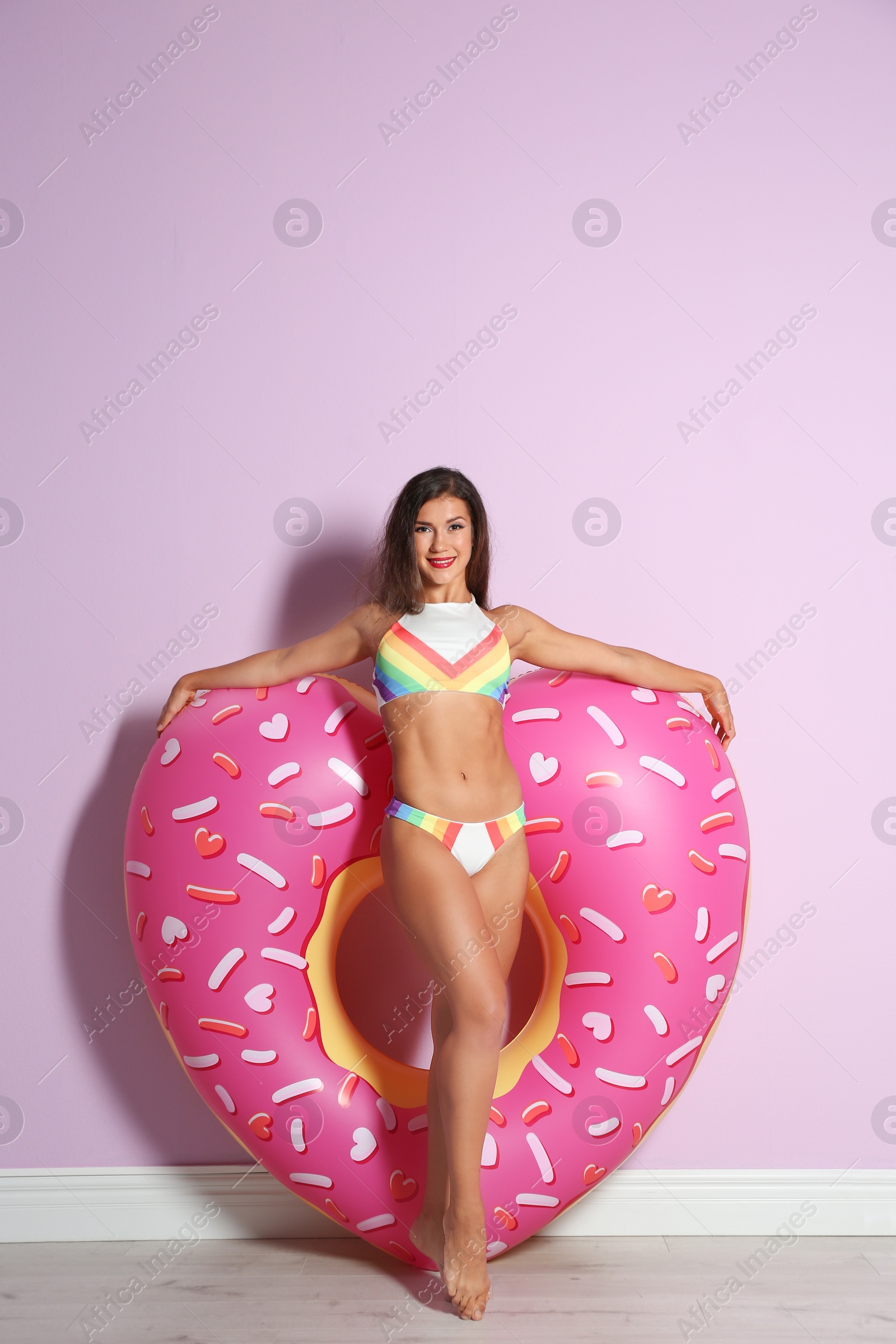 Photo of Beautiful young woman with inflatable heart near color wall