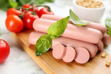 Photo of Fresh raw vegetarian sausages, soybeans and tomatoes on white marble table, closeup