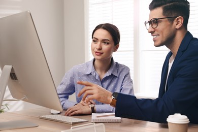 Businessman helping intern with work in office