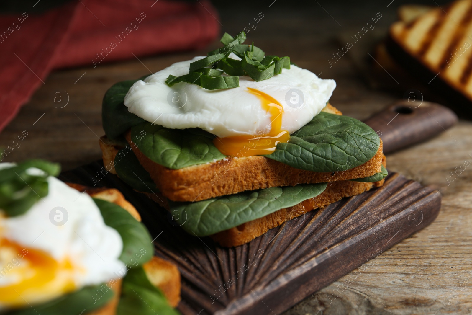 Photo of Delicious poached egg sandwich served on wooden board