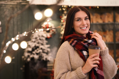 Beautiful woman with cup of coffee in decorated cafe. Christmas celebration