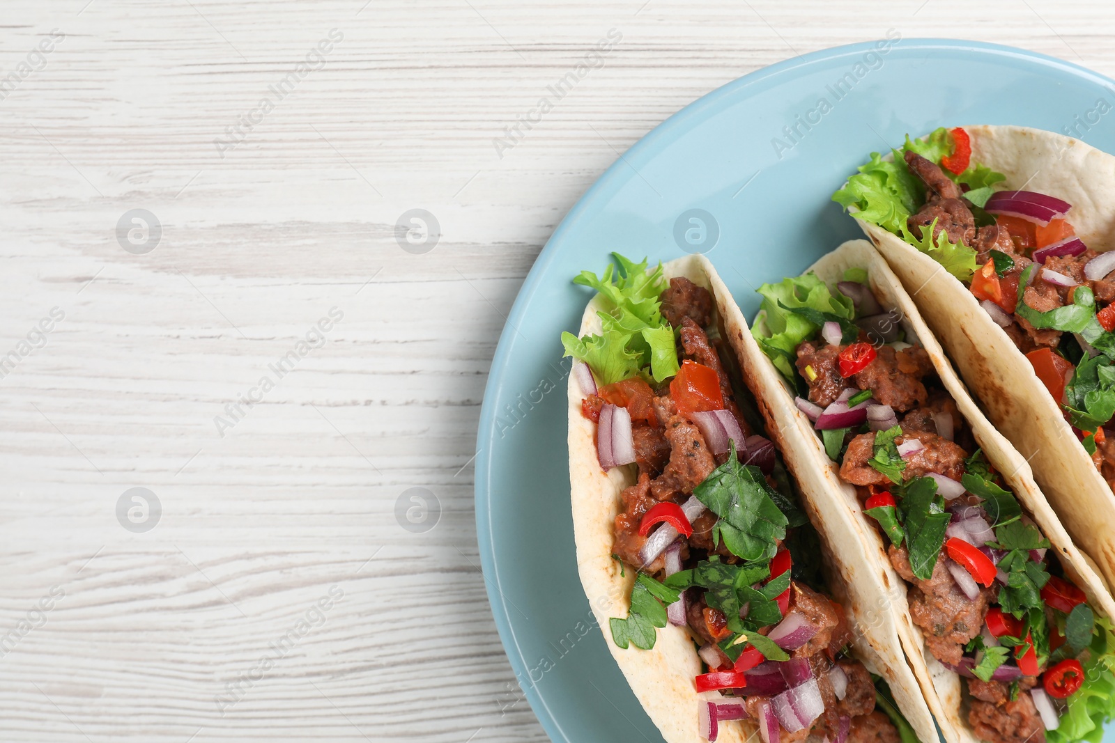 Photo of Delicious tacos with meat and vegetables on wooden table, top view. Space for text