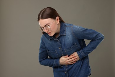 Photo of Woman suffering from stomach pain on grey background, space for text
