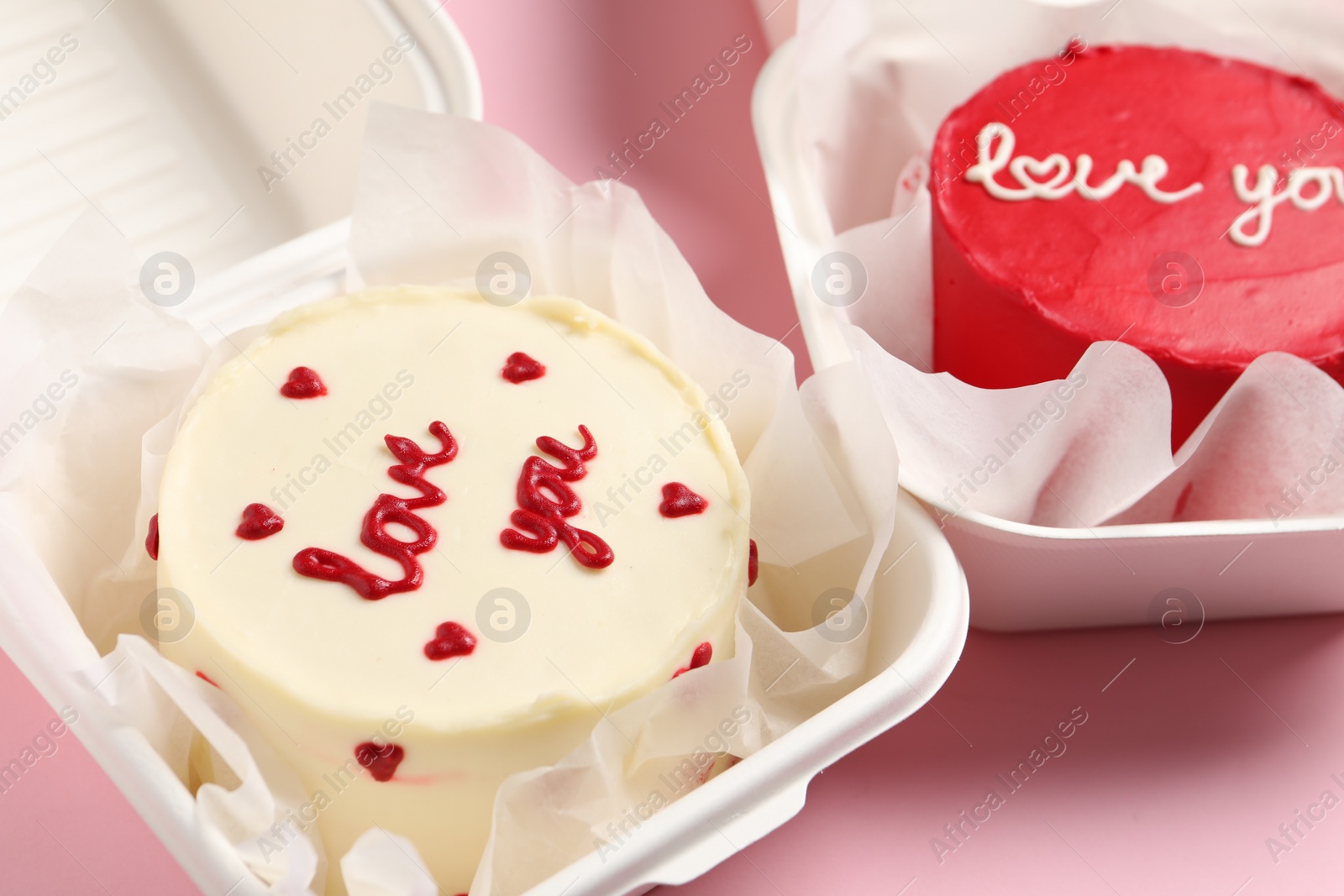 Photo of Bento cakes in takeaway boxes on pink table. St. Valentine's day surprise