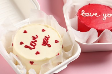 Photo of Bento cakes in takeaway boxes on pink table. St. Valentine's day surprise