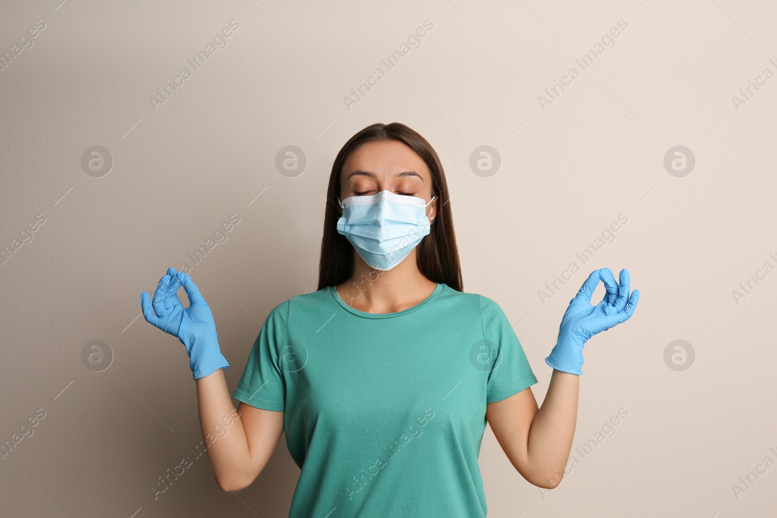 Photo of Woman in protective mask meditating on beige background. Dealing with stress caused by COVID‑19 pandemic