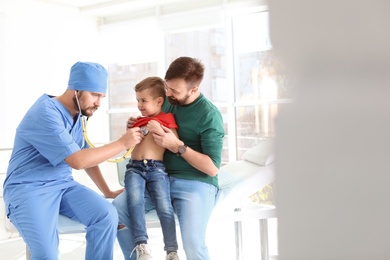 Children's doctor examining little boy with stethoscope in hospital. Space for text