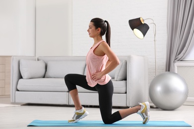 Young woman in fitness clothes doing exercise at home