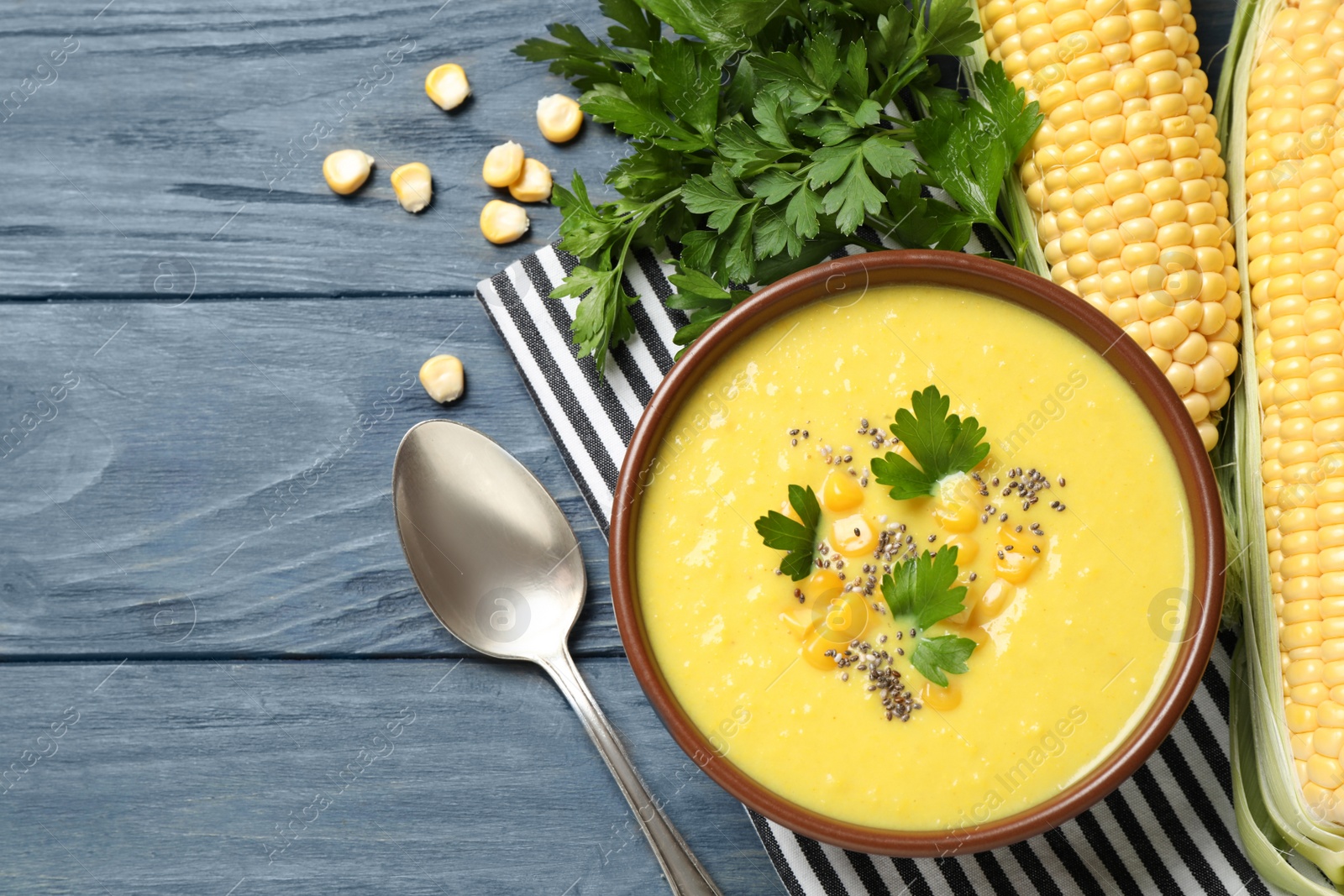 Photo of Delicious corn cream soup served on blue wooden table, flat lay