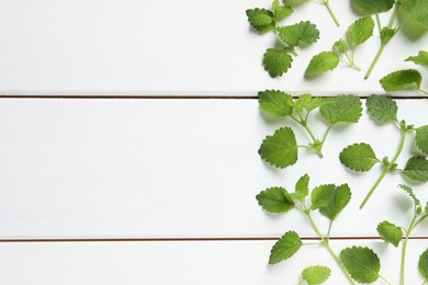 Photo of Fresh lemon balm leaves on white wooden table, flat lay. Space for text