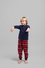 Photo of Boy in pajamas sleepwalking on light gray background