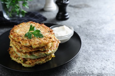 Photo of Delicious zucchini fritters served on grey table, closeup. Space for text