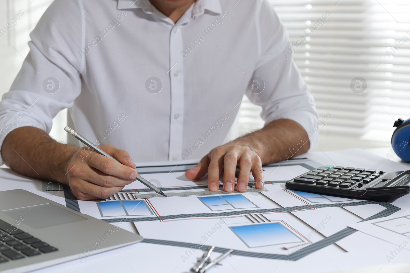 Photo of Architect working with construction drawings in office, closeup