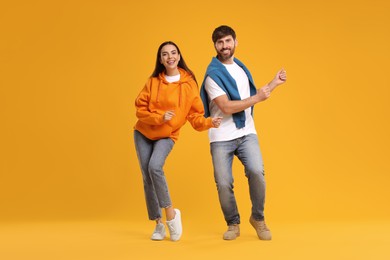 Photo of Happy couple dancing together on orange background