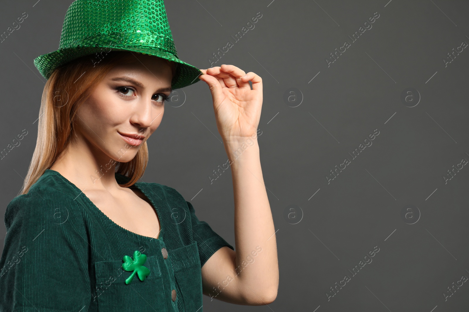 Photo of Young woman in green outfit on grey background, space for text. St. Patrick's Day celebration