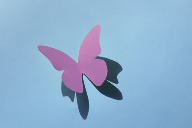 Bright pink paper butterfly on light blue background