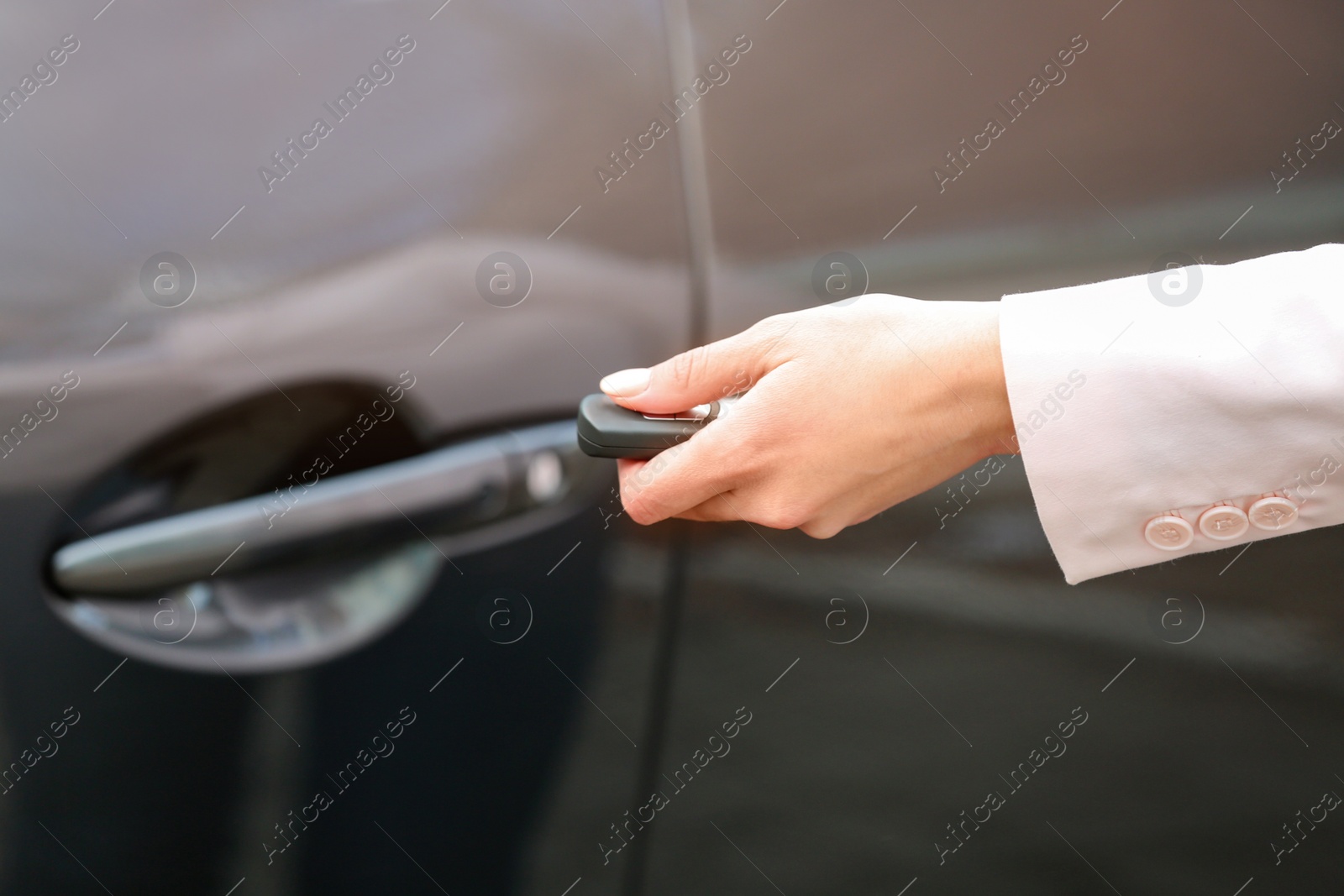 Photo of Closeup view of woman opening car door with remote key