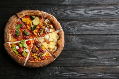 Photo of Slices of different delicious pizzas on black wooden table, top view. Space for text